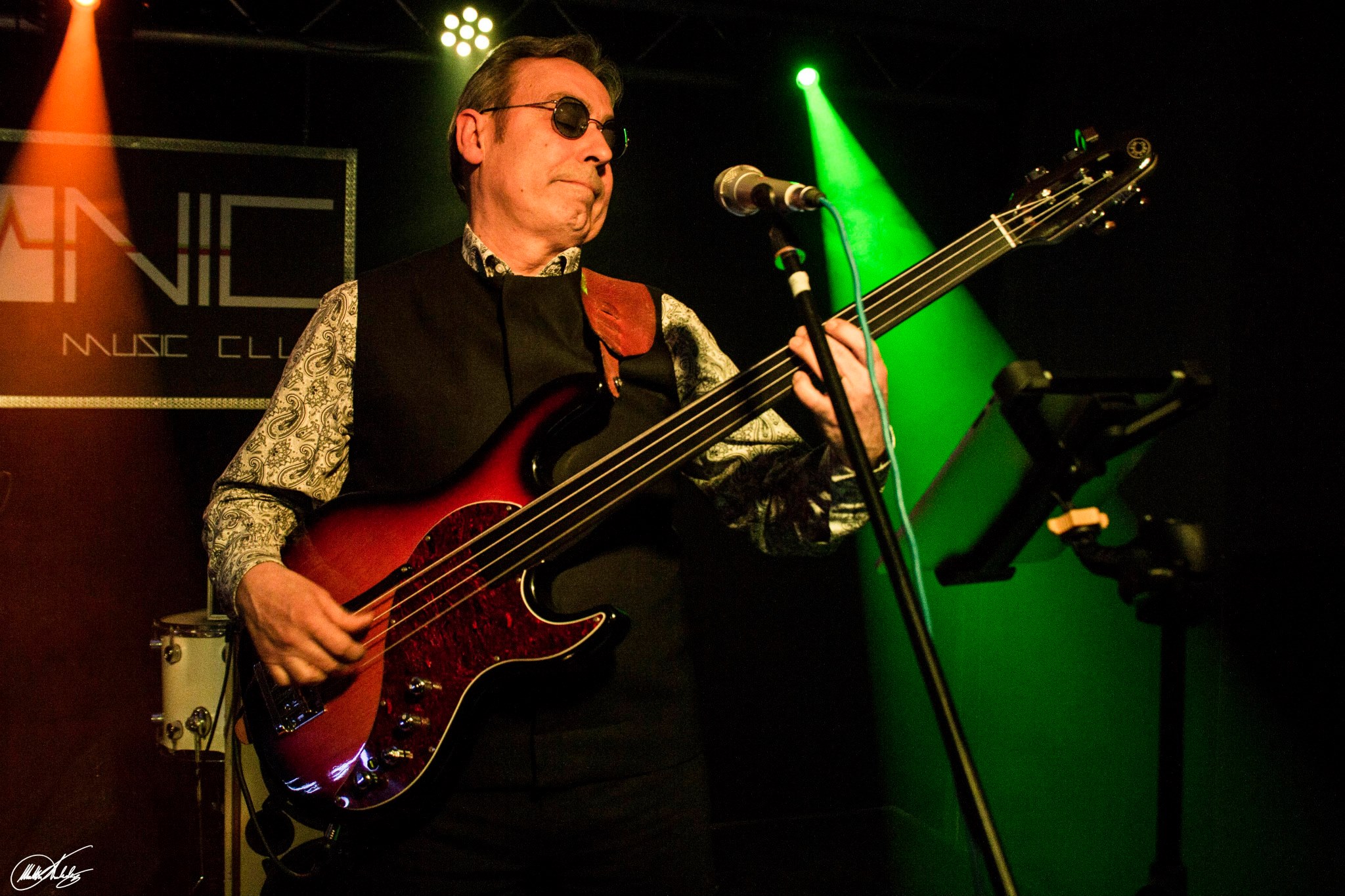 Bozorius on stage playing a red fretless bass under green lights